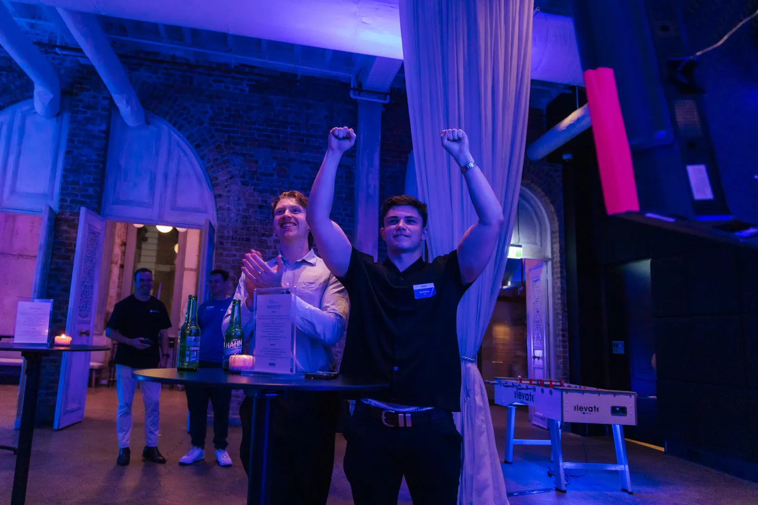 A guest celebrating with both arms raised at Elevate