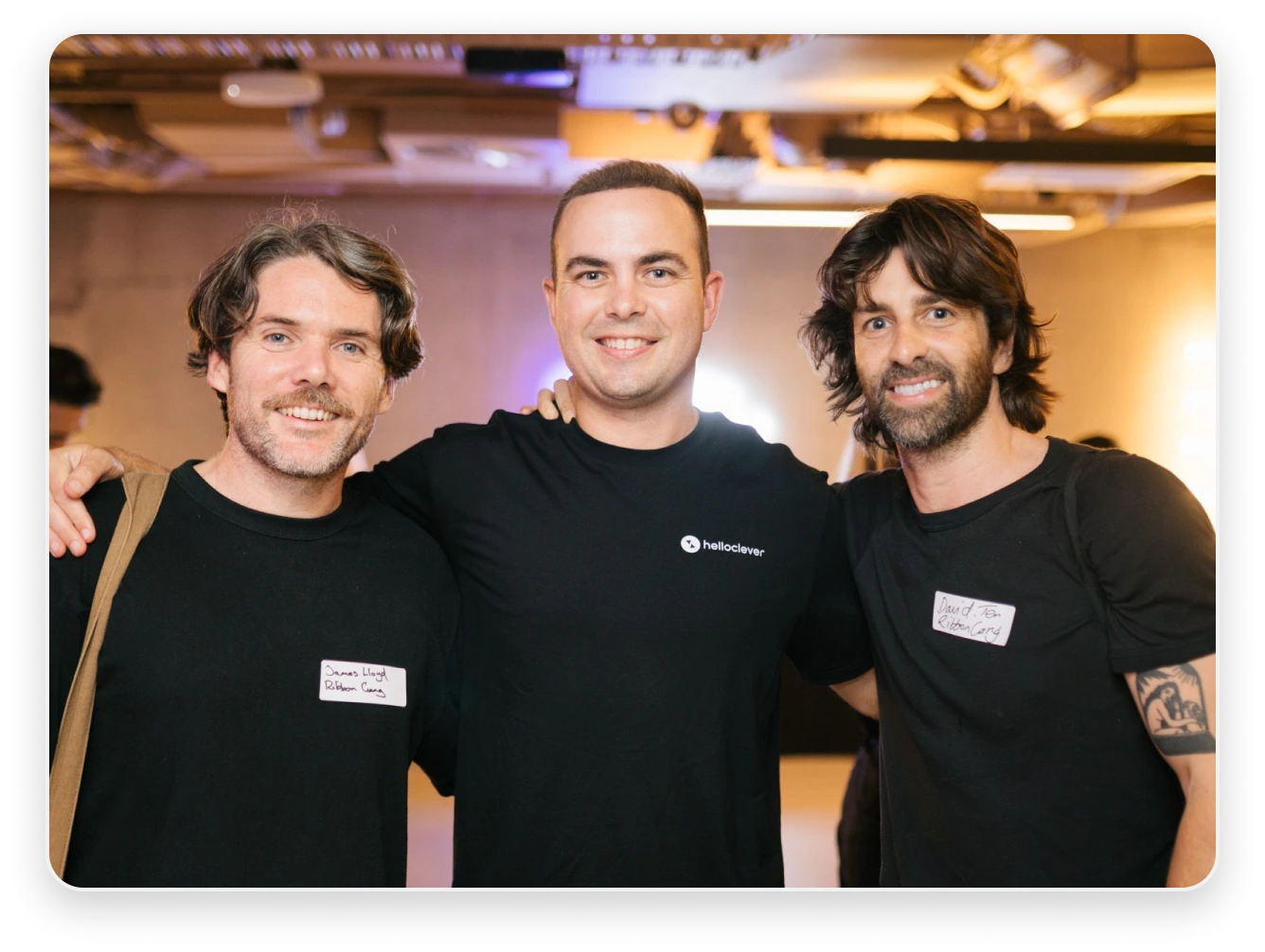 Three Hello Clever team members with their arms around each other at an event
