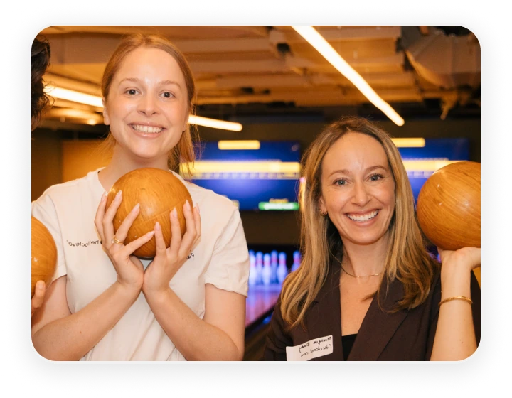 Two guests holding bowling balls at a Hello Clever partner event